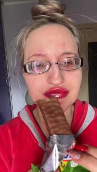Fată uriașă cu buze mari, ochelari cu ochelari, asmreating Snickers Protein Bar