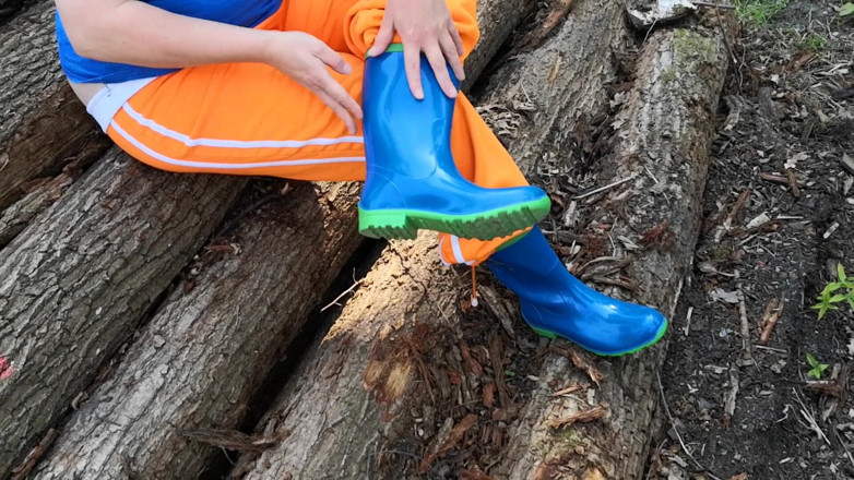 Bouncy Tits Action: Sitting in rubberboots on woodpile