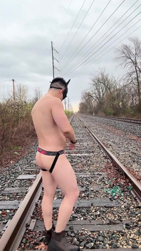 Просочений дощем азіатський мускулистий бог у Jockstrap підстрибує на члені, показує v-taper і їсть своє величезне навантаження на залізничних коліях