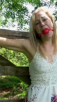 Domsel amarrada ao portão Desacascala Bondage e Ballgagged