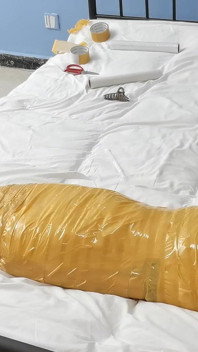 Eine süße barfüßige Freundin benutzt Klebeband, um ihren ganzen Körper zu binden, spielt mit ihren süßen nackten Füßen