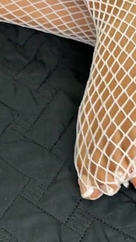Zwart meisje pronkt met haar voeten met Franse pedicure in haar blanke visnetten