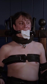 Ricky na židli na bondage, ocelový roubík a polstrování ponožek.