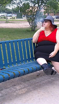 Krankenschwester Vicki raucht im park auf einer bank, ganz angezogen