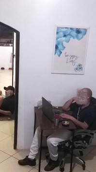 Enquanto o marido trabalha, a esposa em uma toalha saúda o entregador