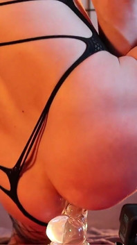 Un niño con un cuerpo hermoso monta un gran consolador transparente