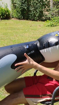 Bell'uomo gonfia la sua balena gonfiabile vicino alla piscina fuori