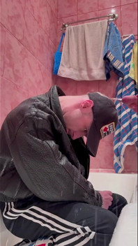 Der russische Gopnik in Lederjacke und Sportschuhen nimmt einen Urinstrahl von einem kräftigen Kerl