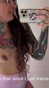 Une fille tatouée à la langue partagée sent ses aisselles poilues après s’être entraîne
