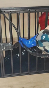 Latex officier neukt zijn latex gevangene met een voorbinddildo