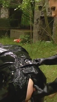 Chlap v latexových šatech ponížený na zahradě