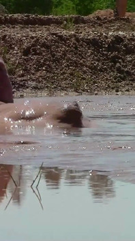 Mandi lumpur dalam lubang pasir dengan lumpur coklat yang dalam, berkrim.