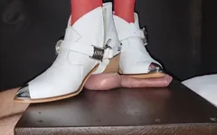 Des bottes blanches écrasent des couilles et se tiennent debout sur la table
