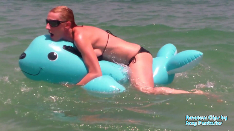 Brittany Lynn: Neukend blauw opblaasbaar speeltje in het water op een strand...