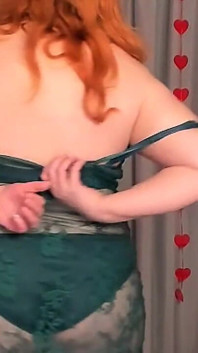 Rijpe roodharige dame 50+ striptease in transparante smaragdgroene jurk