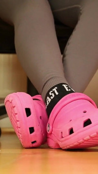 Jeu de pieds sous le bureau - sabots roses et chaussettes usés