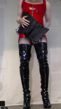 Il travestito si veste con stivali, calze a rete, abito in pvc rosso e corsetto