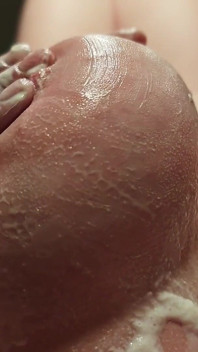 Een naakte vrouw met enorme tieten in een massagesalon die slagroom gebruikt.