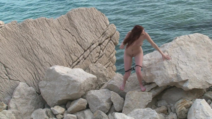Cryptostudios: Gorąca brunetka loszka pozowała nago na skałach przy plaży