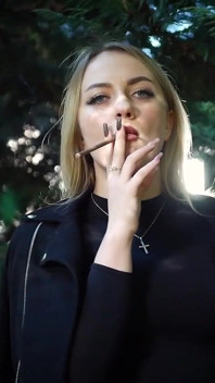 Gagică blondă sexy care fumează două țigări negre în natură