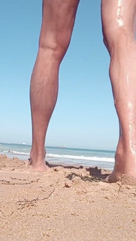 Un giovane apre i glutei sulla spiaggia mentre gli altri guardano.