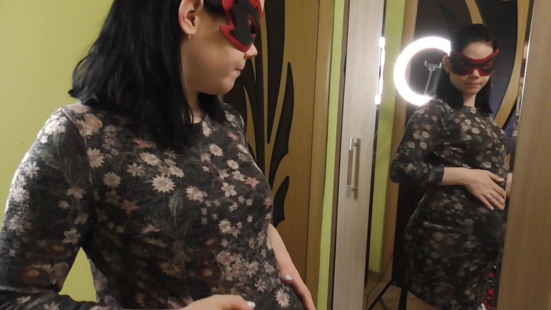 Anna Sky: Anna, enceinte, essaye des robes devant un miroir