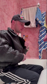 Ruský chlap gopnik v kožené bundě a sportovních botách bere proud moči od silného chlapa