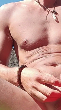 Seorang pria seksi di pantai masturbasi dan menelan spermanya.