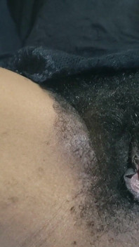 Una milf caliente y un coño peludo en primer plano se masturban