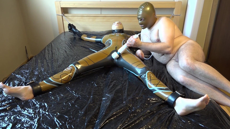 Latex Danielle: Latex Danielle is attached to the bed and masturbated with...