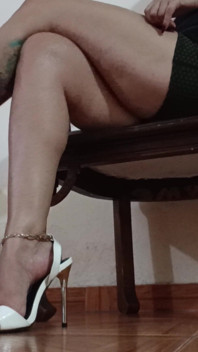 Her Long Legs Are Crossed, and Her High Heels Dangle From Her Feet as She Sips a Delicious Cup of Coffee
