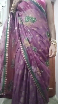 インドのゲイ女装者ボトム・ガウリシシーが紫のサリーで大きな胸を押さえつけ、遊びながら重いジャネリーを纏っています