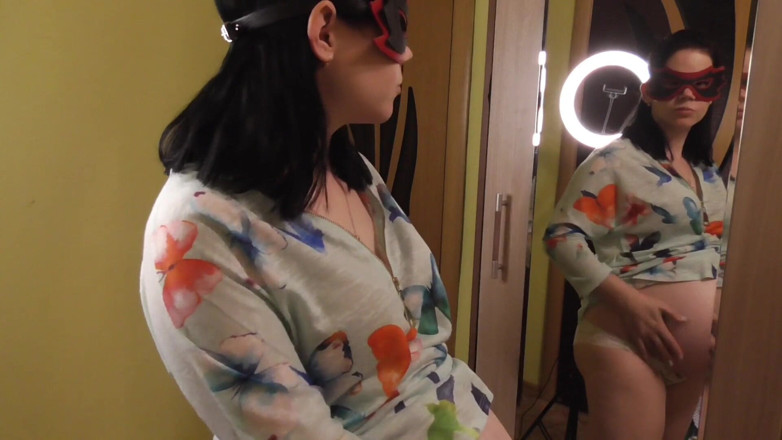 Anna Sky: Anna, enceinte, essaye des robes devant un miroir