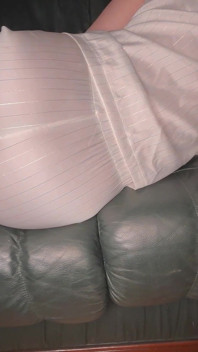 Pète dans un pyjama en satin blanc sur un canapé en cuir vert