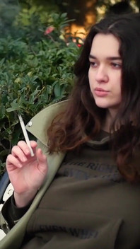 Young Brunette Is Taking an Unhurried Stroll with Allwhite 120mm Cigarette