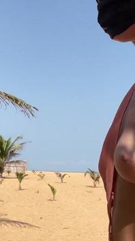 Blonde à forte poitrine marche et montre son corps nu sur la plage