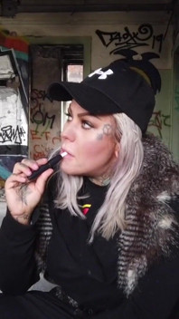 Blonde dame raucht eine elektronische zigarette auf dem treppenhaus