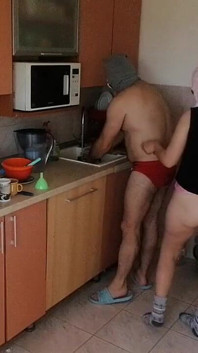 キッチンで楽しんでいるカップル。裸で家事をするセクシーな妻