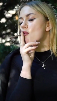 Gorąca blonde babe palenie dwóch czarnych papierosów w naturze