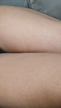Uma mulher com muitos pelos púbicos bonitos entre as pernas está em seu sofá esperando para ser feita amor para ela