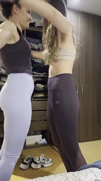 两个女人穿上健身房的衣服，玩女性手臂和屁股摔跤比赛。