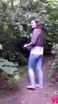Desperate Brunette with Long Legs in Tight Jeans Walking Trough Forest Searching for a Place to Pee