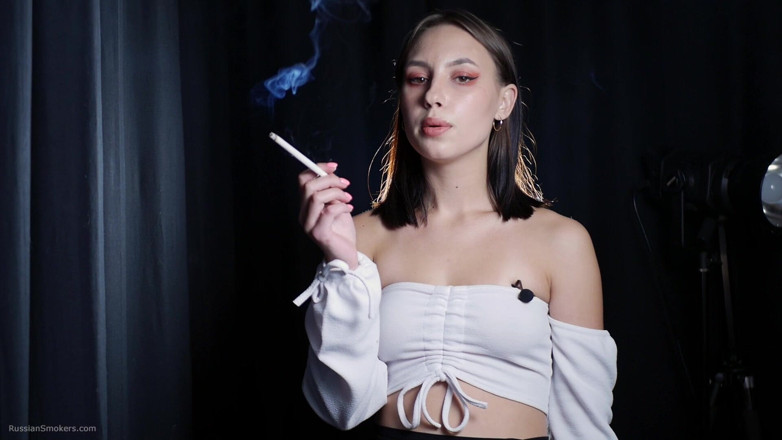 Russian Smokers: Si rambut coklat yang elegan merokok dalam adegan studio gelap