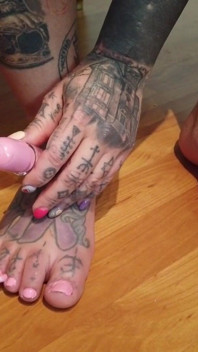 La signora bionda tatuata si dipinge le unghie dei piedi