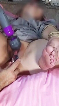 Sentada de pernas cruzadas, fazendo-a gozar com um vibrador.
