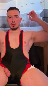 Luchador flexionando los músculos y masturbándose una carga enorme
