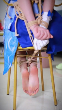 Cosplayt zijn vriendin comfortabel op een stoel met touwen, haar benen hangend