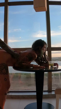 Dreadhot curvado sobre a mesa de vidro enquanto a cidade inteira podia ver