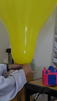 Marianna tenta inflar seu balão quadrado sem explodi-lo