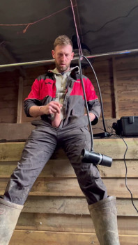 Farmář kouří a dojí se s dojicím strojem